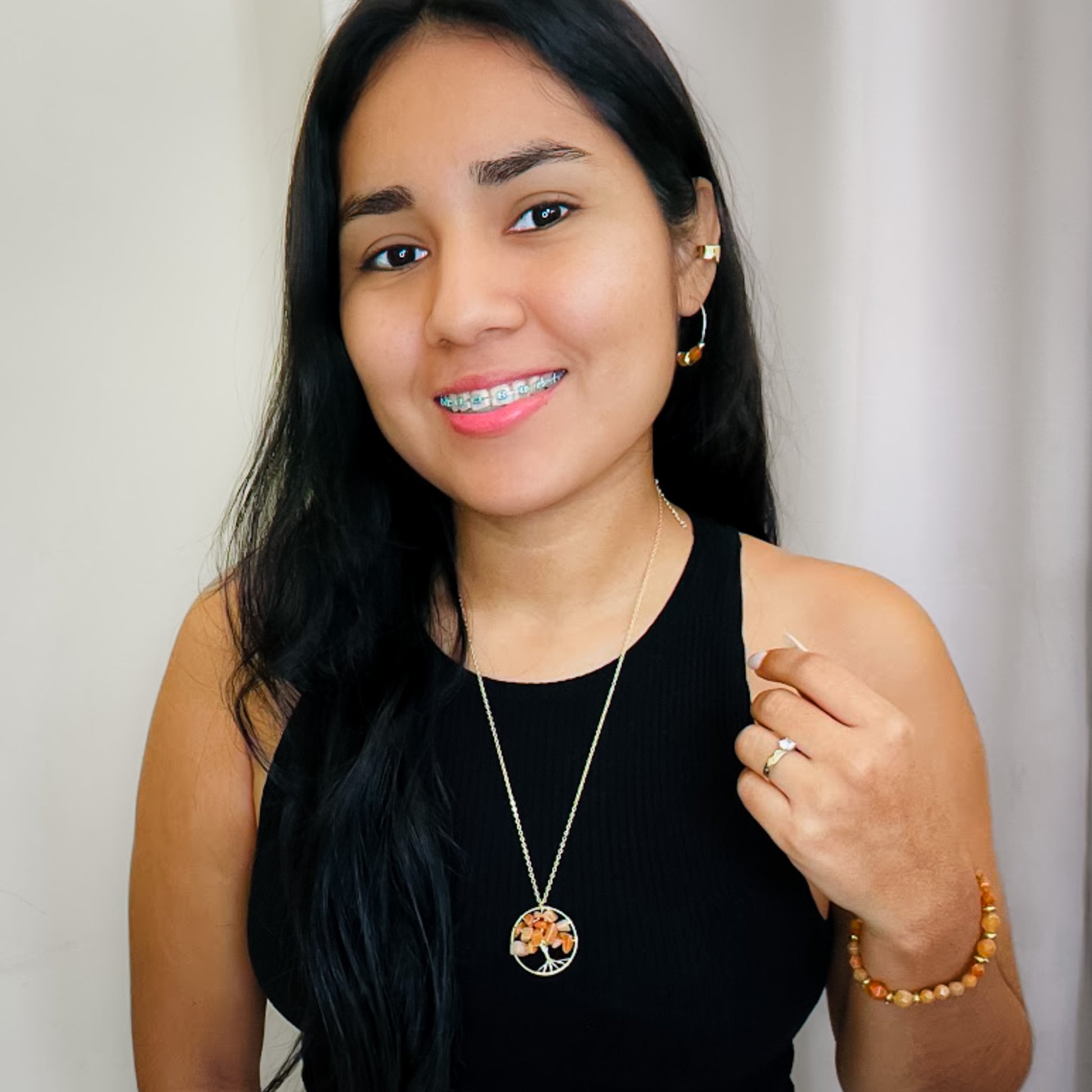 Woman wearing a black top with a gold and orange agate tree of life necklace