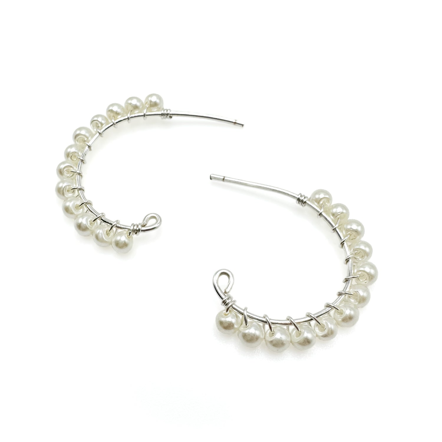 Pair of silver hoop earrings with pearls on a white background