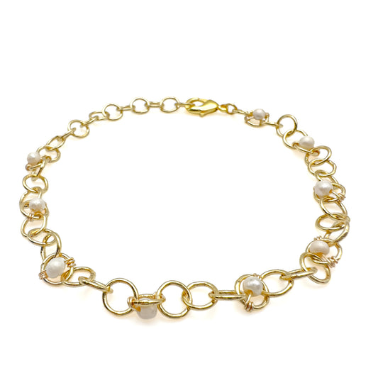 Gold chain bracelet with pearls on a white background