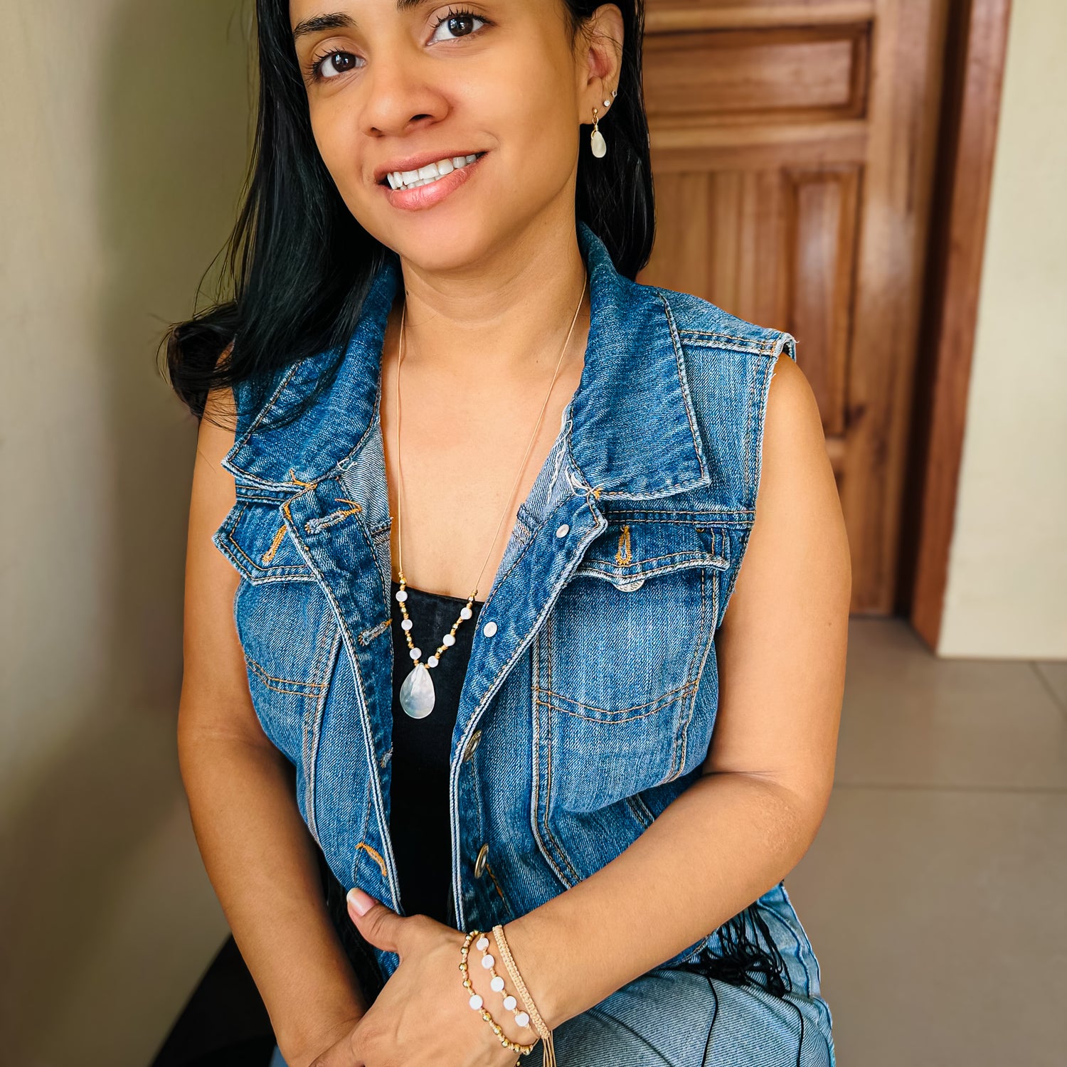 Woman modeling adjustable tan cord necklace and bracelet with gold and mother of pearl beads and teardrop mother of pearl drop earrings