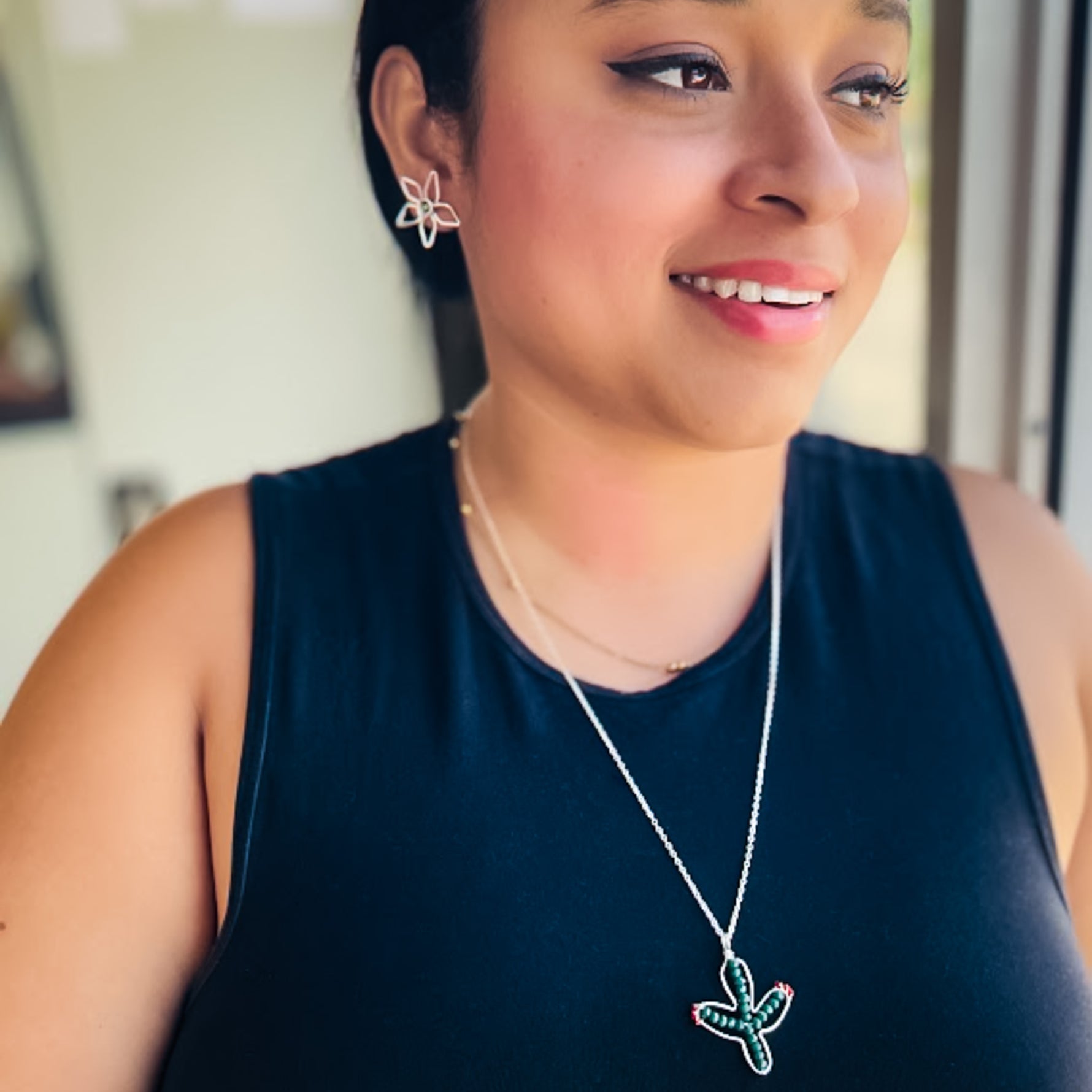 Woman modeling silver jewelry set including silver wire flower post earrings and green and red blooming cactus pendant necklace