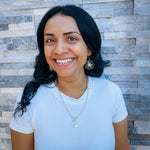 Woman modeling silver jewelry including silver and pearl large flower dangle earrings and short silver chain necklace with silver heart pendant with the word Hope on it