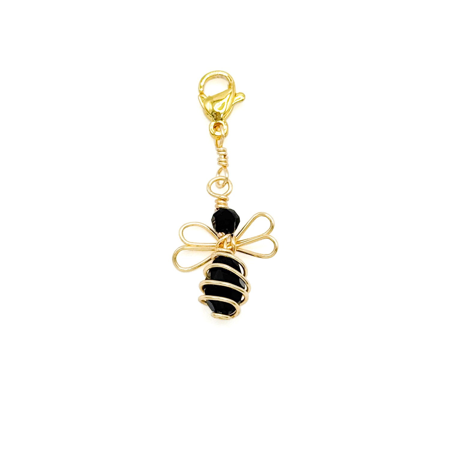 Gold and black bee-shaped charm on a white background
