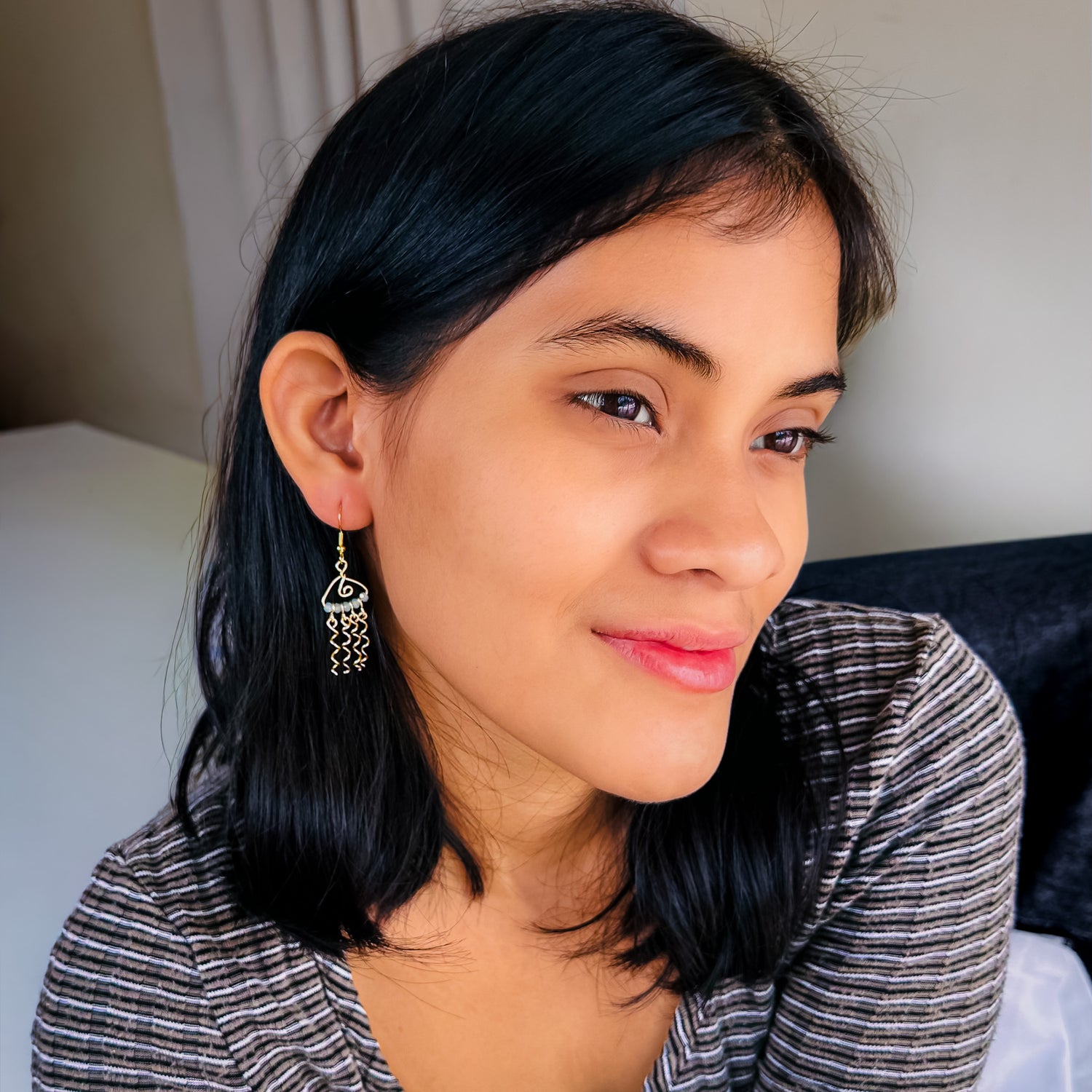 Woman modeling gold and blue-green crystal jellyfish dangle earrings