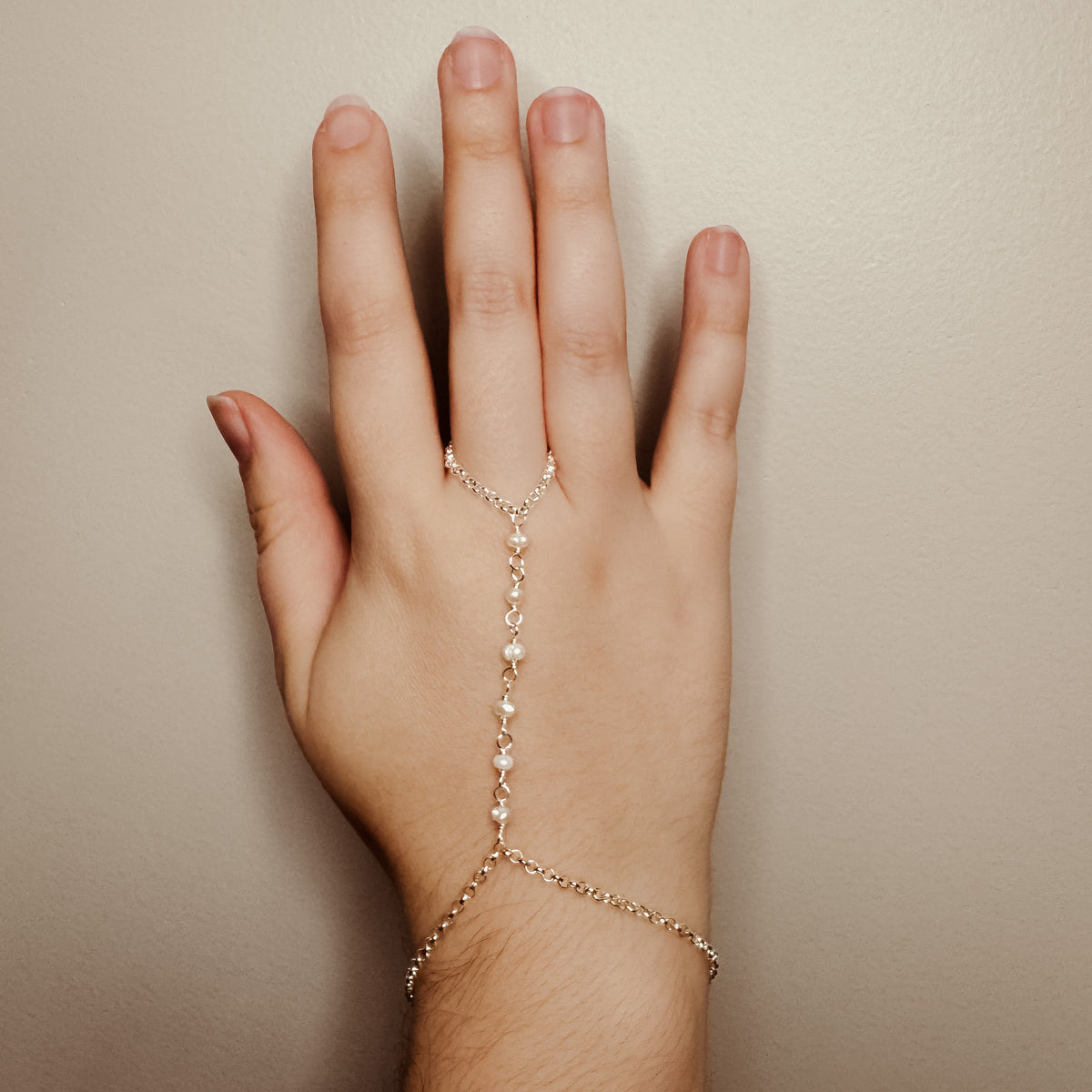 Silver and freshwater pearl hand chain bracelet modeled on a hand