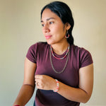Woman modeling gold, pearl, and coral agate jewelry set including memory wire bangle bracelet, teardrop dangle earrings, and multistrand beaded and chain necklace