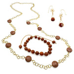 Gold and goldstone jewelry set including intricate flower dangle earrings, beaded adjustable cord bracelet, and long chain and station bead necklace