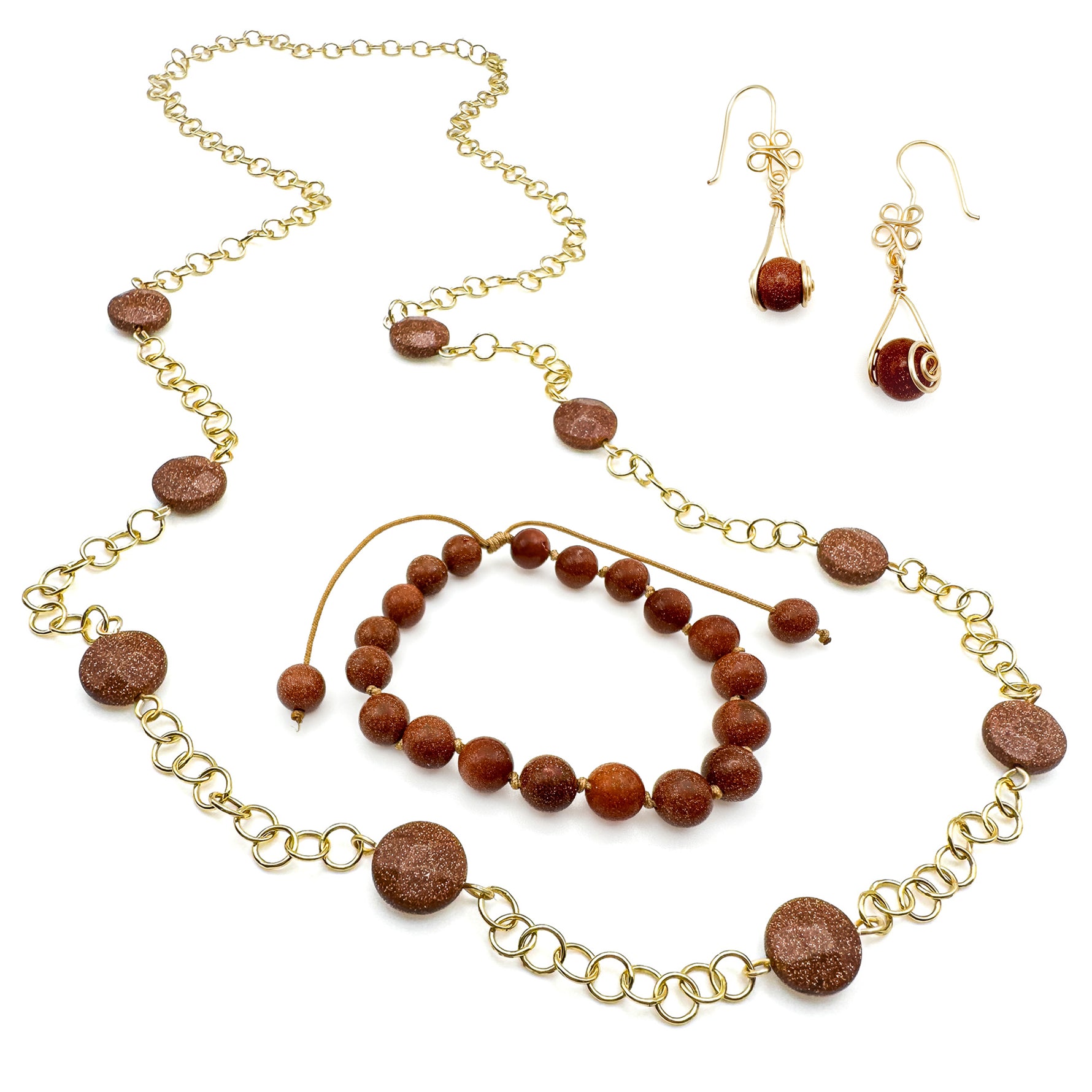 Gold and goldstone jewelry set including intricate flower dangle earrings, beaded adjustable cord bracelet, and long chain and station bead necklace