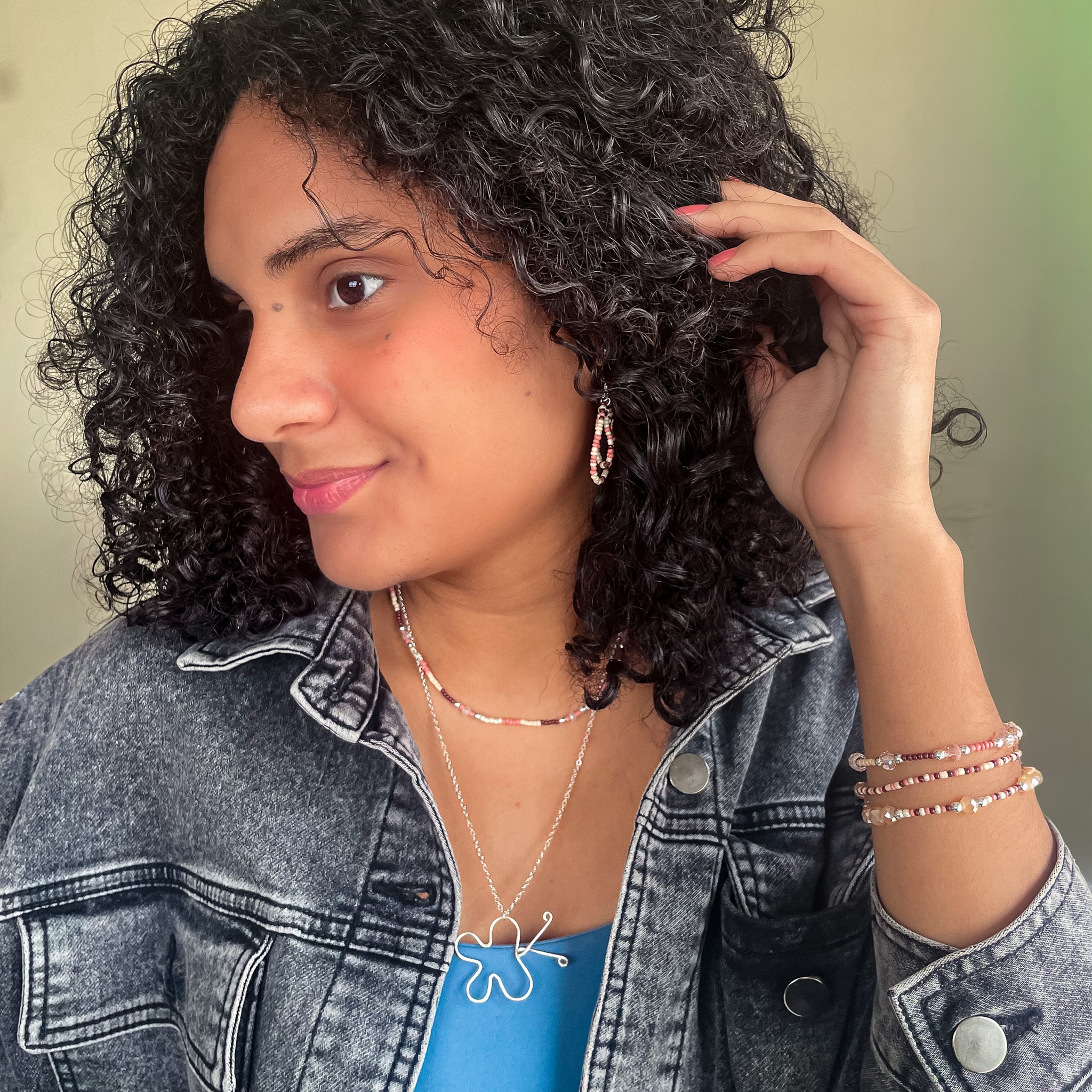 Woman wearing a denim jacket and blue top modeling peach and brown silver jewelry set with butterfly pendant