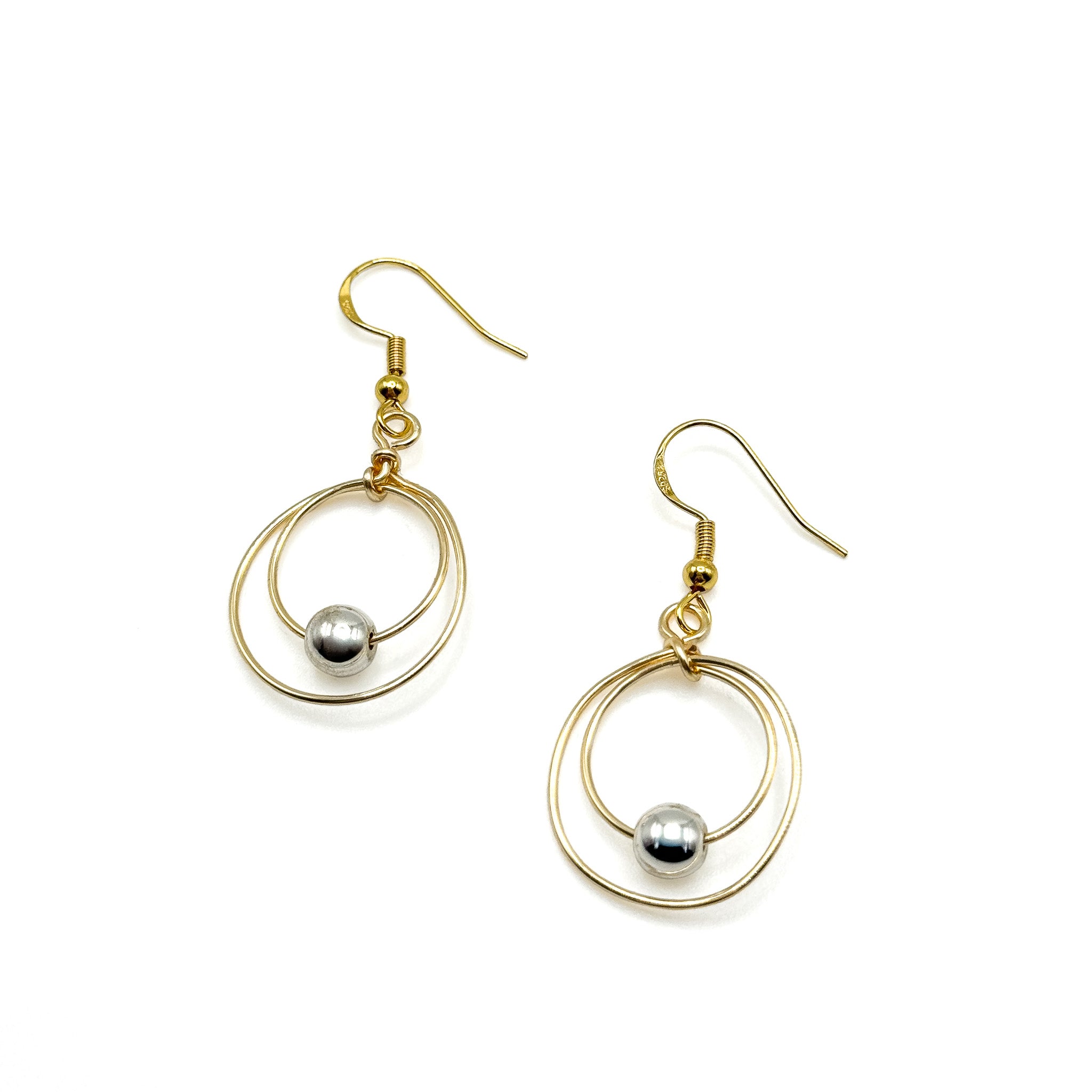 Gold concentric circle dangle earring with silver bead in the center