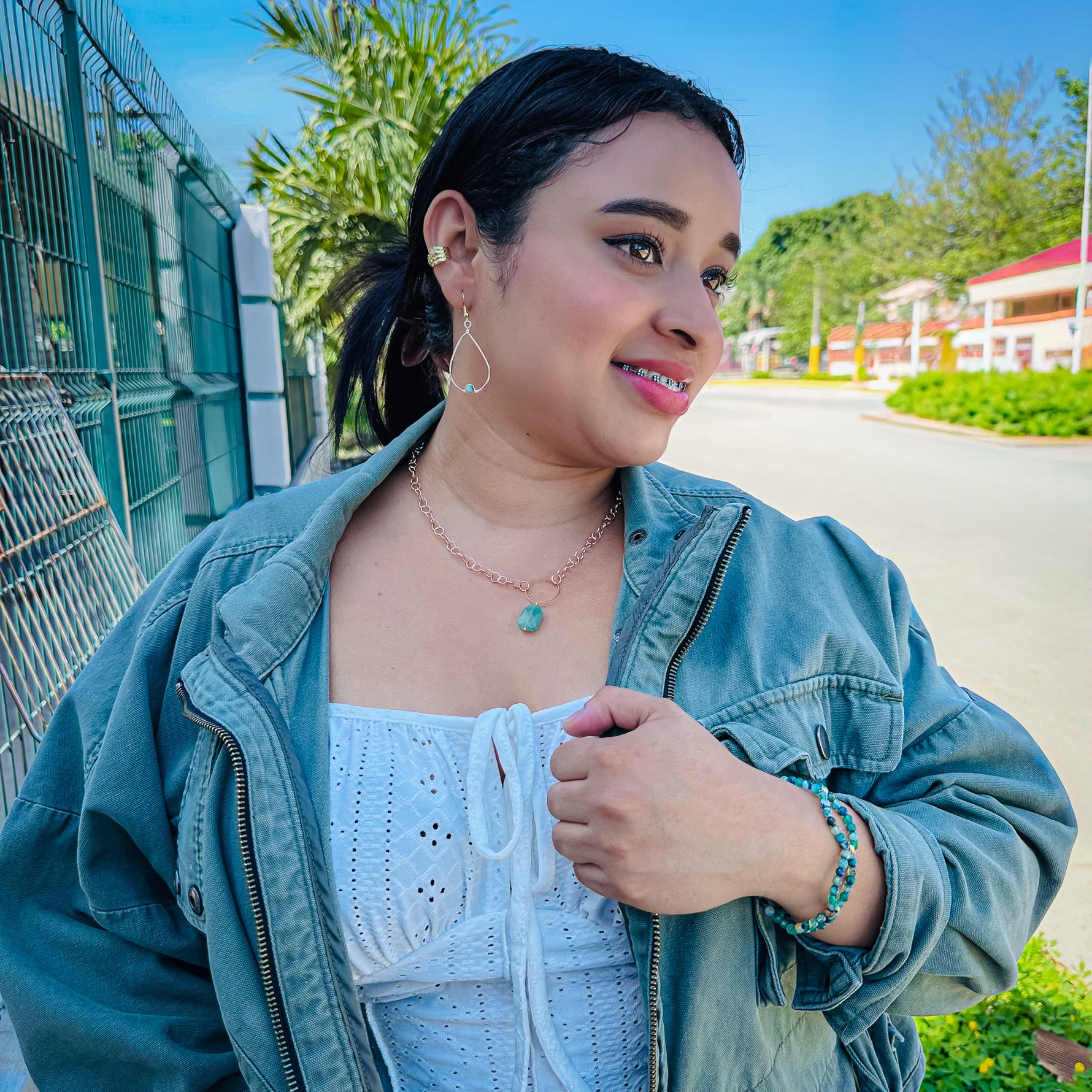 Woman modeling gold and green agate jewelry set with teardrop dangle earrings, beaded stretch bracelet, and green aventurine stone pendant necklace