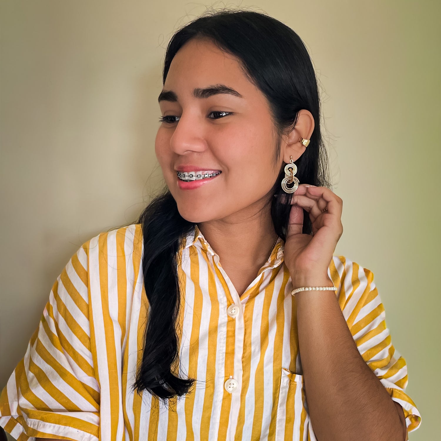 Woman modeling large gold concentric circle geometric dangle earrings
