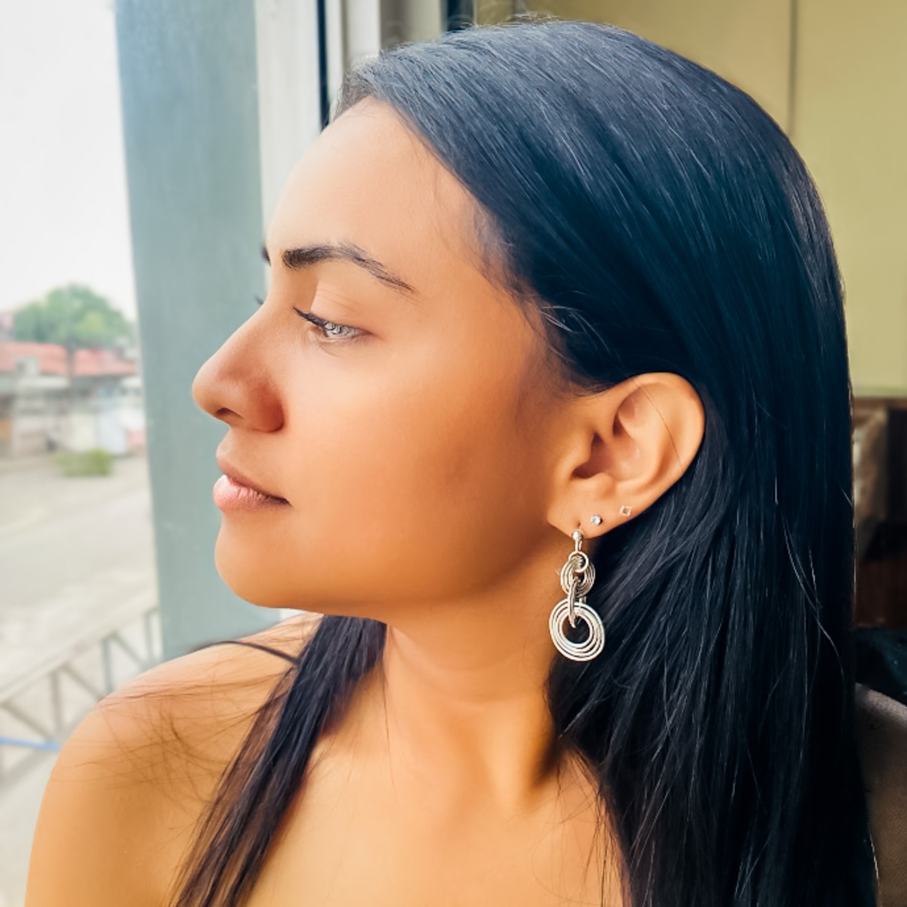 Woman modeling large silver concentric circle geometric dangle earrings