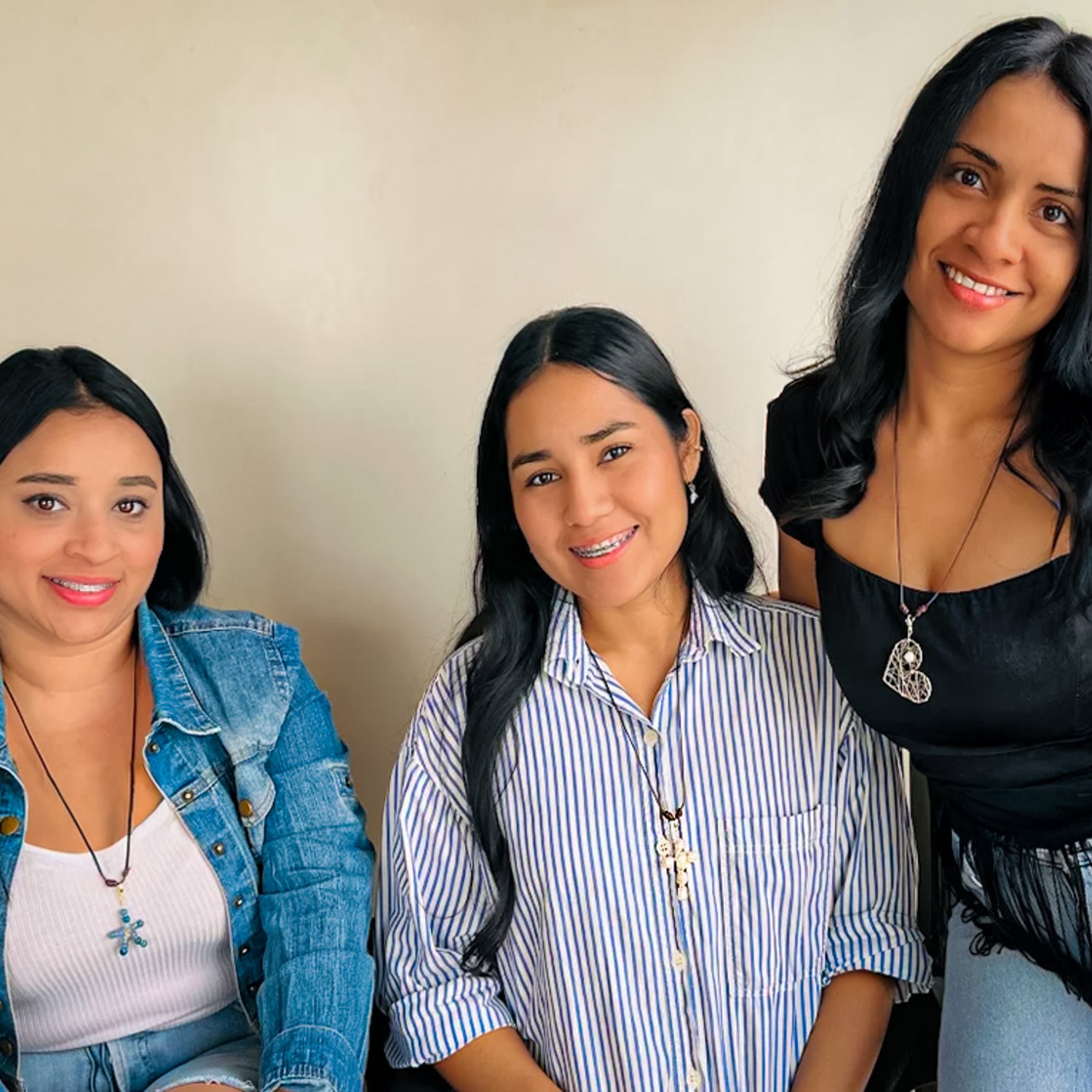 Three women modeling the same brown adjustable cord necklace with three different starfish, cross, and heart pendants