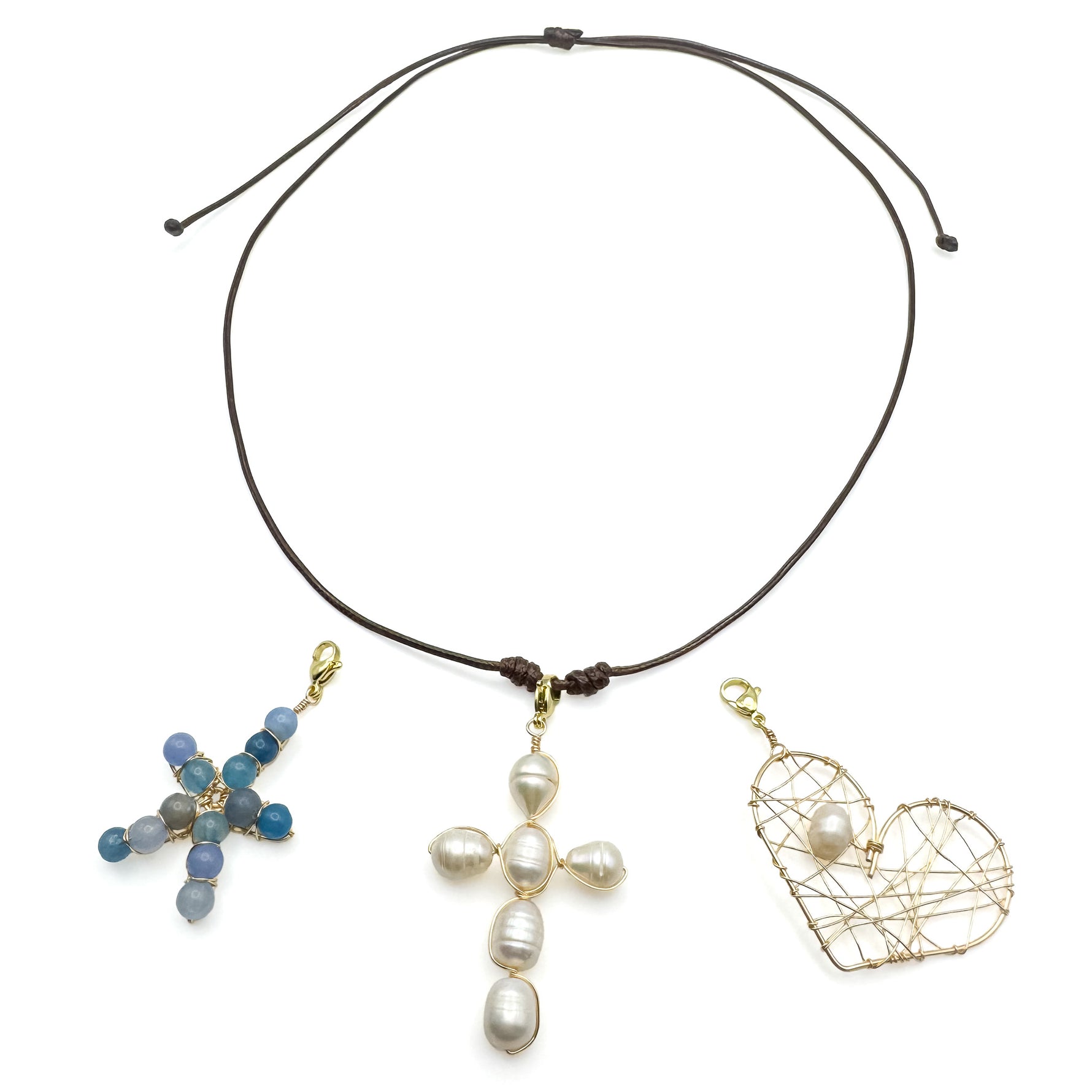 Brown adjustable cord necklace with blue agate starfish, pearl cross, and woven gold and pearl heart interchangeable pendants