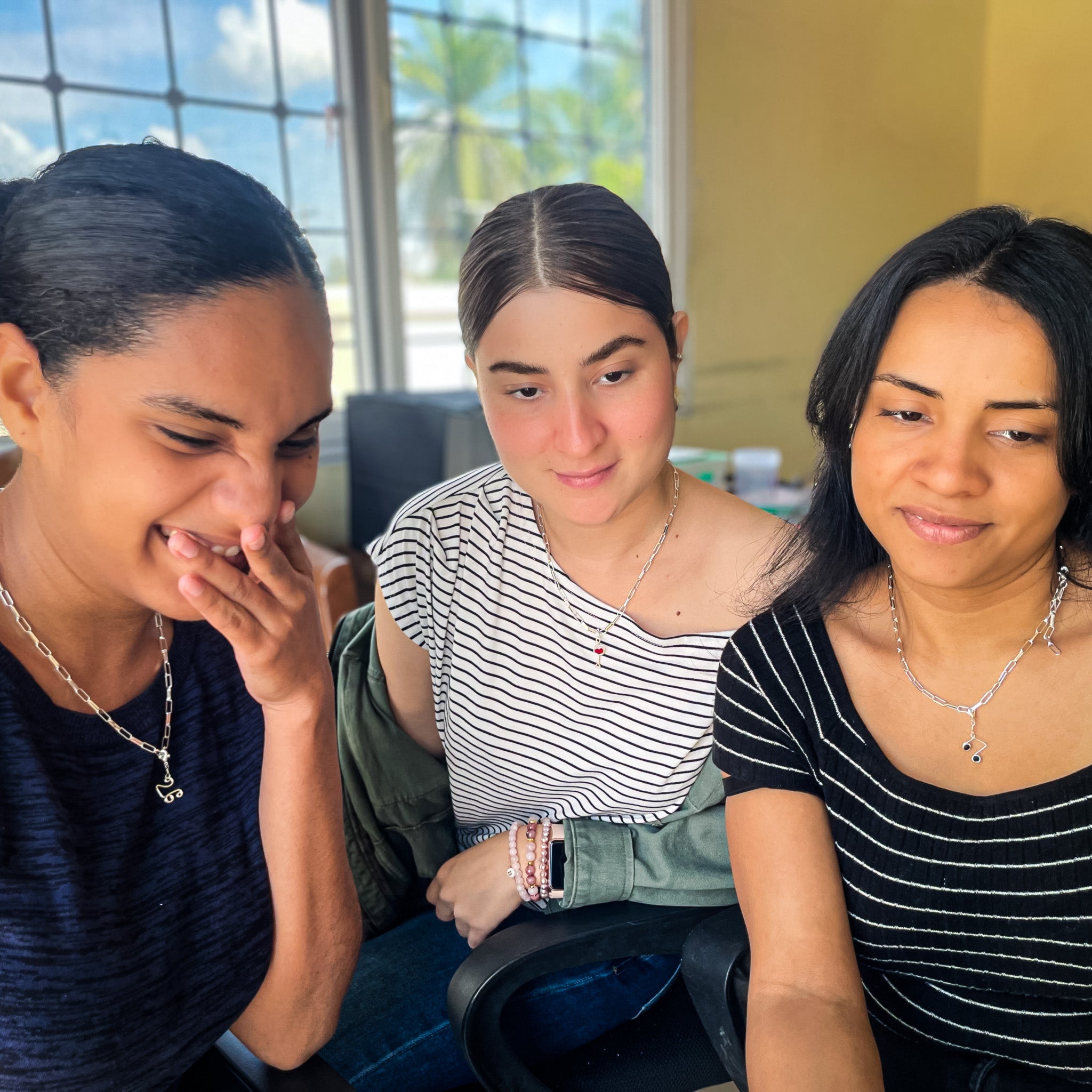 Woman modeling silver charm necklaces including '26', wine glass, and music note charms