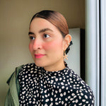 Woman modeling gold starfish dangle earrings with peach crystal design