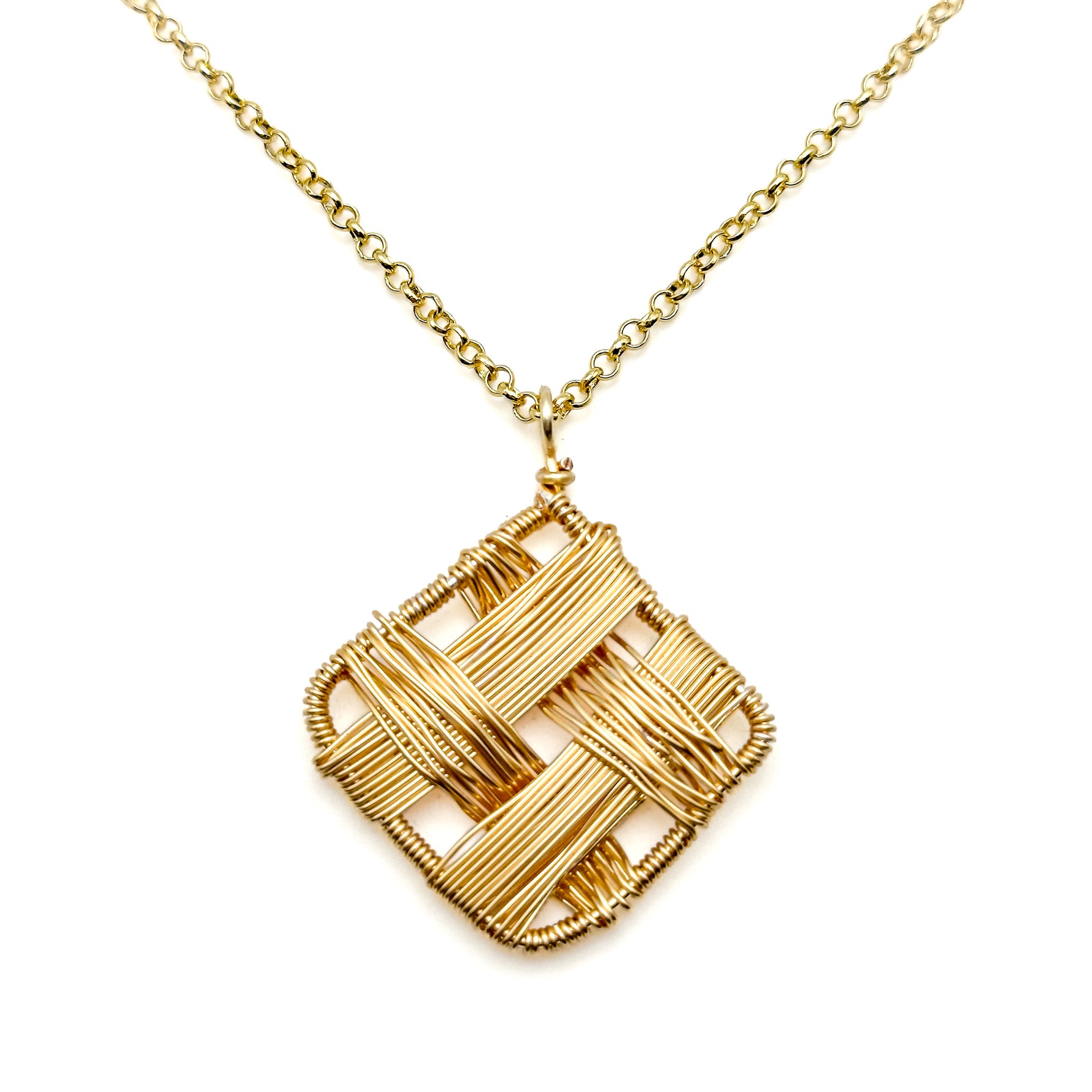 Close up of chunky gold necklace with intricate, interwoven pattern on pendant