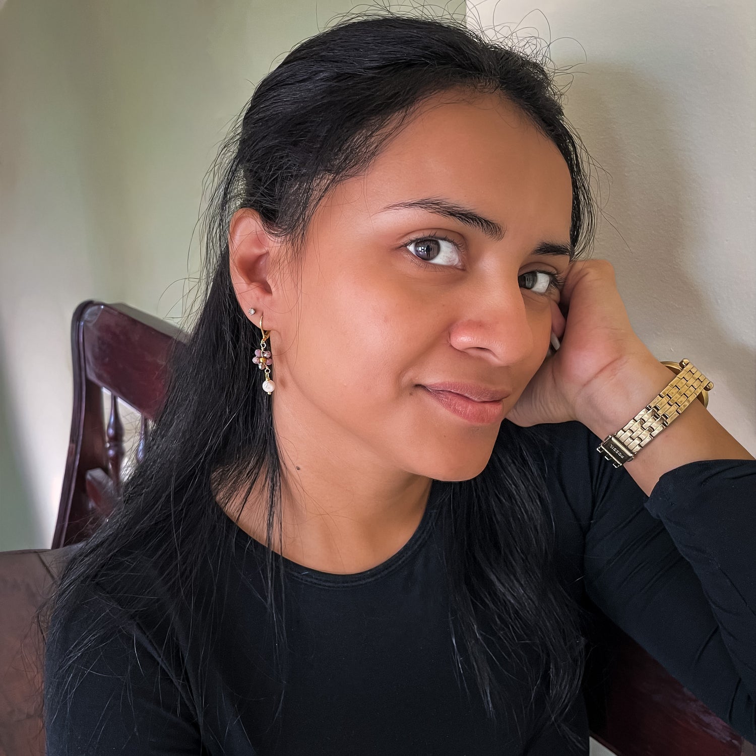 Woman modeling gold dangle earrings with brown crystal flower ending in freshwater pearl drop