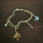 Gold and silver two-tone paperclip chain bracelet with four charms including silver rose flower, gold christmas tree, silver cancer ribbon, and silver and blue ceramic teapot